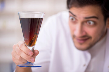 Young male chemist examining soft drink