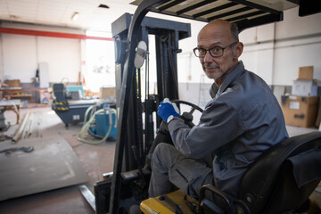 Fototapeta na wymiar A worker drives the mechanical forklift during work in the warehouse.