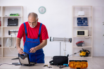 Old repairman repairing sandwich maker at workshop