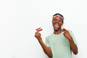 happy black man holding up money and debit card isolated against white background