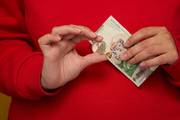 Woman in red hoodie holds green Georgian paper banknote 50 GEL. Shopping payment concept. Money to...
