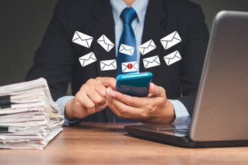 Businesswoman using a smartphone receives a new message with email icons while sitting at the table