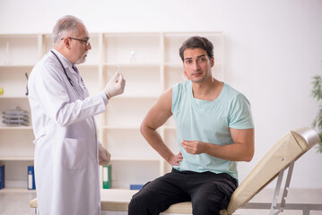 Fototapeta premium Young male patient visiting old male doctor in vaccination conce