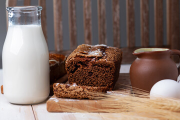Black rye bread with raisins, homemade. Milk, spikelets of rye and eggs on the kitchen table. Selective focus.