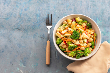 Healthy food broccoli salad add apple chickpeas in white bowl on blue wood background.