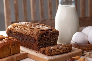 chocolate cupcake on a wooden board, a bottle of milk and eggs on the table. Close-up.