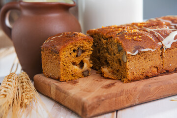 piece of chocolate muffin on the kitchen table and a bottle of milk in the background.