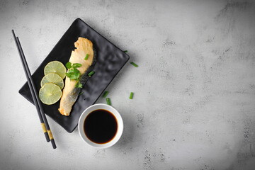 1 piece of salmon served in Japanese style in a black plate at a Japanese restaurant.