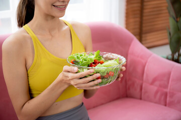 Happy young caucasian woman holding salad vegetable in bowl for eating lettuce in living room at home, female satisfied and vegetarian food for healthy and nutrition, lifestyles and health concept.