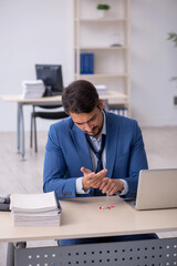Fototapeta premium Young male employee suffering at workplace
