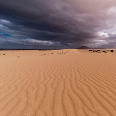 Atlantic ocean, sand dunes and dark volcano under stormy and rainy heaven, Corralejo, Fuerteventura 