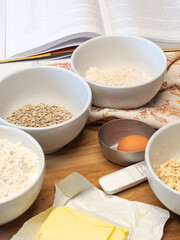 Some of the ingredients for baking bread placed next to a cook book.