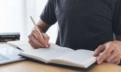 University student using laptop or computer for studying or learning book, reading textbook at home. Knowledge and skill training online at home. Education and cognition success idea concept