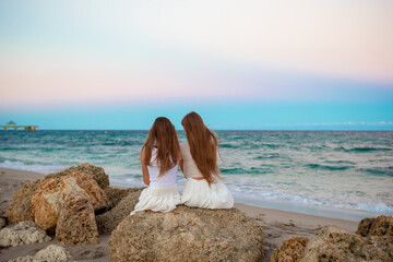 Fototapeta na wymiar Two sisters enjoy sunset on the beach