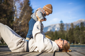 Happy family. Young mother playing with her baby boy infant oudoors on sunny autumn day. Portrait...
