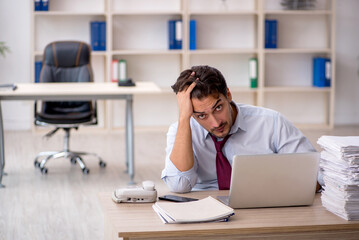 Young male employee and too much work in the office