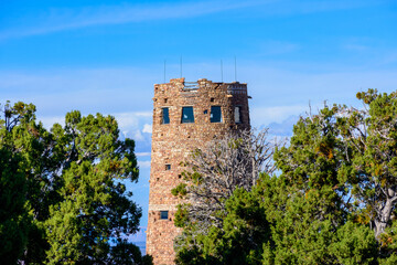 Fototapeta premium Desert View Watchtower behind green trees at Grand Canyon