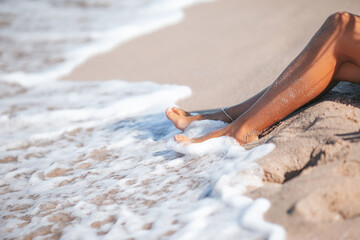 Closeup of woman legs splashing in shallow water on the beach - 551435811