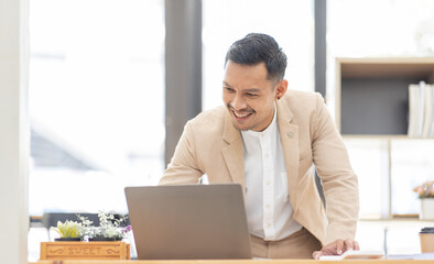 Young business Asian man working at workplace with laptop and papers on desk