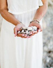 white sea stones in the hands of a girl with a beautiful manicure, close-up