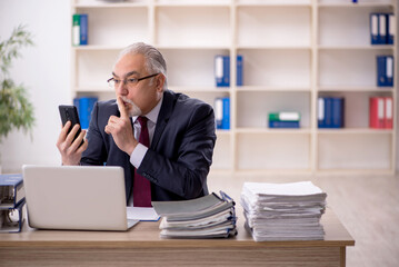 Old male employee sitting at workplace