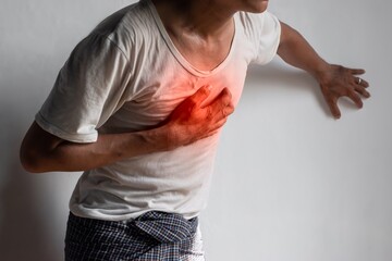 Asian man suffering from central chest pain. Chest pain can be caused by heart attack, myocardial...