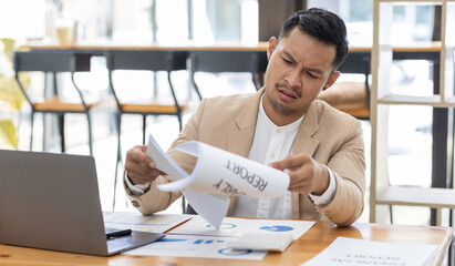 Portrait of tired young business Asian man work with documents tax laptop computer in office. Sad,...