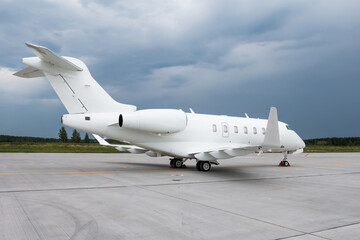 Fototapeta na wymiar White business jet on the airport apron on a cloudy day