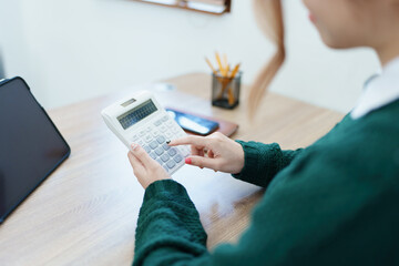 business owner or Asian female marketers are using calculator to calculate and tablet computer in office work