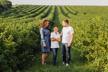 Fototapeta premium Young family looking at the camera while walking in the garden