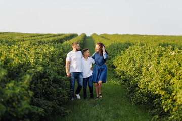 Fototapeta premium Young family looking at the camera while walking in the garden