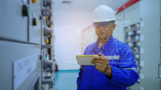 Electrical engineer working in substation building checking electrical current and voltage sine wave  by hologram displayed on mobile screen, Energy industrial work concept and modern technology.