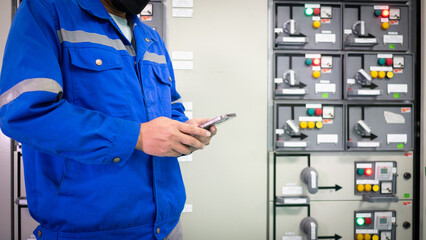 Electrical engineer working in substation building checking electrical current and voltage sine...