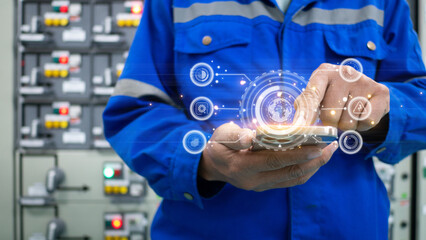 Engineer in electrical control room of industrial plant is using mobile application to check...