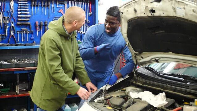 Owner of car explains the problem with car engine to mechanic of the car service. High quality 4k footage