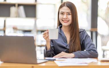 Asian Businesswoman Using laptop computer and working at office with calculator document on desk, doing planning analyzing the financial report, business plan investment, finance analysis concept.
