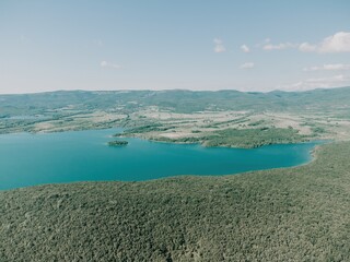 Aerial view on mountain lake. Drone over water reservoir at mountain valley covered with green spring forest. Beautiful view from above on smooth blue surface of mountain lake among highlands. Nobody