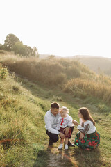 Beautiful family with kid in traditional ethnic dress in a countryside, park