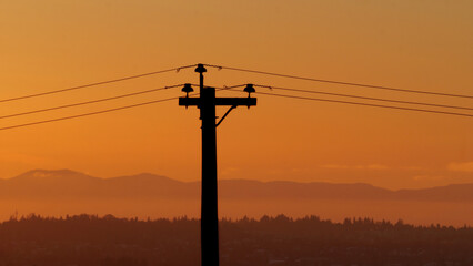 Silhouette of an electric wire pole during a sunset over Metro Vancouver in British Columbia, Canada