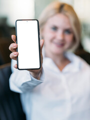 Mobile connection. Digital mockup. Office work. Unrecognizable defocused woman holding smartphone with blank screen in light room interior.