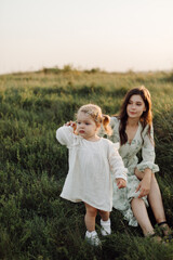 Fototapeta premium Beautiful caucasian family of father, mother and little daughter posing on camera on background of green field