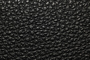 Dark black bumpy textured background image with highlights. Rough leather or animal skin appearance.