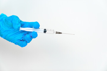 women's hands in blue gloves with a disposable syringe. 