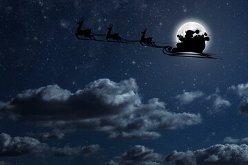 Obraz na płótnie Canvas Santa Claus flies on Christmas Eve in the night sky with snow