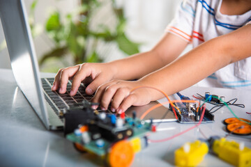 Asian kid boy learns coding and programming with laptop for Arduino robot car, Little child students typing code in computer with car toy, STEAM education AI technology course school learning