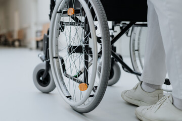 Rear view of caregiver pushing wheelchair at hospital corridor.