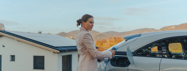 Young woman charging her electric car in home, sustainable and economic transportation concept.