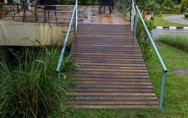 Fototapeta premium Disabled way in front of building. Handicapped traffic symbol on the floor in front of ramp way for support wheelchair. Disabled way in front of cafe on green nature landscape.