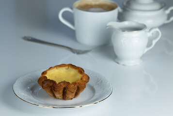 Still life of egg tart on white table with cup of coffee