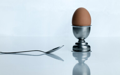 Soft boiled egg on egg cup with spoon against white background